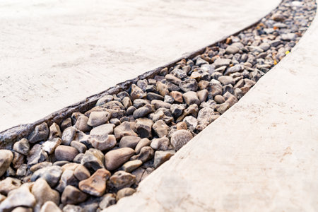 Cement background crossed by a diagonal line of pebbles stone