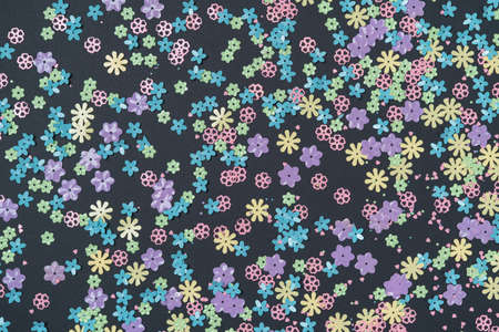 Festive black background with colorful flowers. Multi-colored small artificial flowers. Flat lay, top view.の写真素材