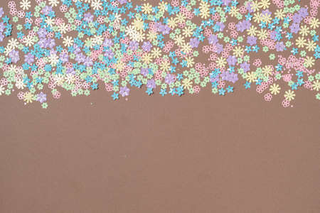Festive brown background with colorful flowers with copy space. Multi-colored small artificial flowers. Flat lay, top view.の写真素材
