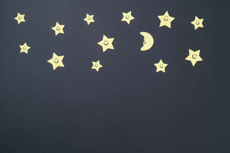 Elements in shape of yellow stars and smiling moon on paper black background. Greeting card design. Flat lay. Top viewの写真素材