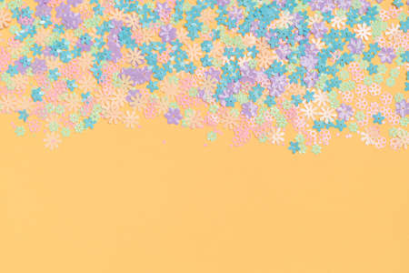Festive orange background with colorful flowers with copy space. Multi-colored small artificial...