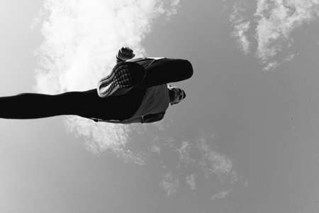 Low angle view of a sportsman who jump and run with blue sky in backgroundの写真素材