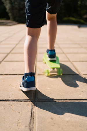 Close up legs in blue sneakers riding on green skateboard in motion. Active urban lifestyle of...