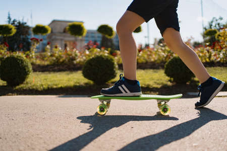 Close up legs in blue sneakers riding on green skateboard in motion. Active urban lifestyle of youth, training, hobby, activityの写真素材