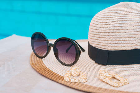 Sunglasses, golden earrings and hat near pool. Vacation time.の写真素材
