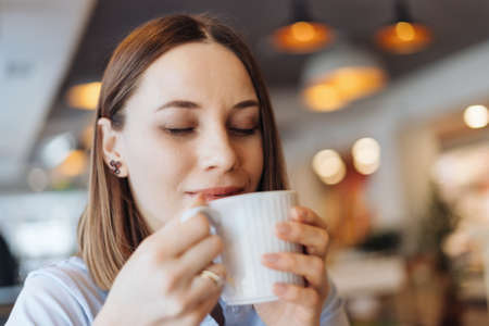 Attractive female with cute smile having a coffee while relaxin in a break