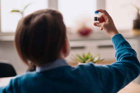 Distance online education, internet learning. First grade boy studying at home using microscope, making notes, biology online lessonの写真素材