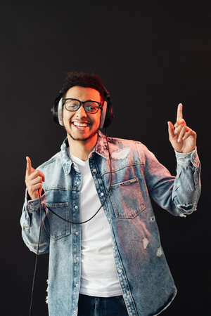 Young African American man wearing headphone and enjoy music over black Background