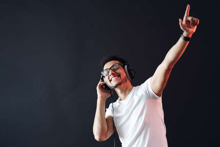 Young African American man wearing headphone and enjoy music over black Background
