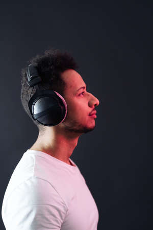 Smile Young African American man portrait wearing headphones and enjoy music over black Background....