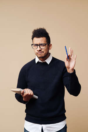 Young Professor holding a book while explaining wearing glasses on beige background. People emotions...