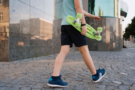 BOY legs in bright clothes walking with PENNY BOARD in the handsの写真素材