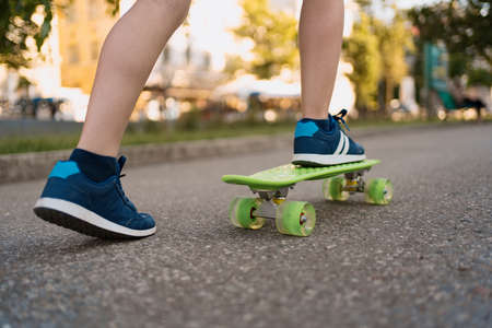 Close up legs in blue sneakers riding on green skateboard in motion. Active urban lifestyle of youth, training, hobby, activityの写真素材