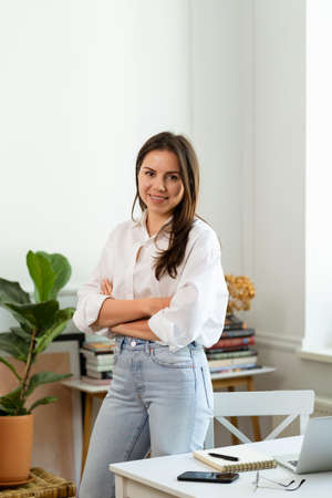 Image of young cheery positive beautiful business woman sitting indoors in office or home office...