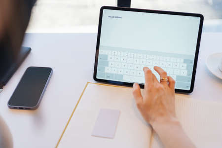 Woman fingers typing on tablet screen HELLO SPRING. Using technologies concept