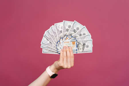 Woman hand with stack of dollars isolated on pink background with copy spaceの写真素材