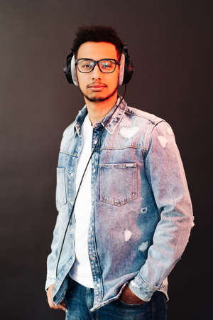 Young African American man wearing headphone and enjoy music over black Backgroundの写真素材