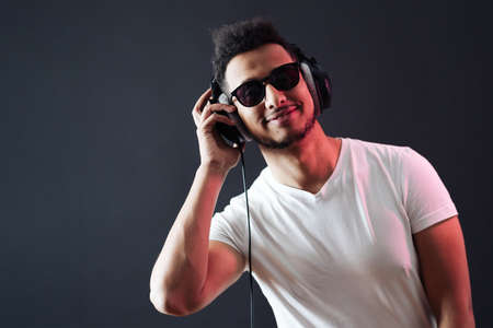 Smile Young African American man portrait wearing headphones and enjoy music over black Background....