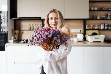 Carefree happy single young attractive woman dancing alone in modern kitchen interior, independent active lady having fun at clean home listening music enjoying freedom weekend time lifestyle at homeの写真素材