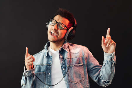 Young African American man wearing headphone and enjoy music over black Background