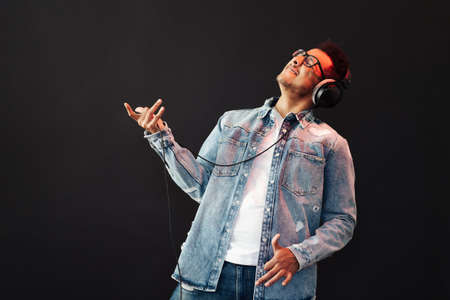 Young African American man wearing headphone and enjoy music over black Backgroundの写真素材