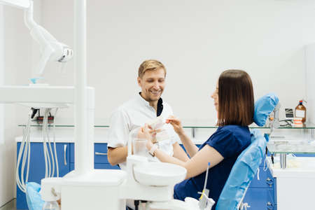 Dentist showing the correct dental hygiene using mock-up of skeleton of teeth. Stomatologist doctor...
