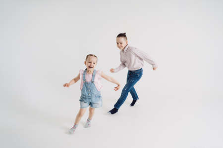 Playful brother and sister running and playing on white background. Two kids having funの写真素材