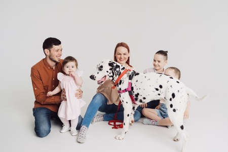 Young Family with kids playing with a dalmatian dog on white backgroundの写真素材