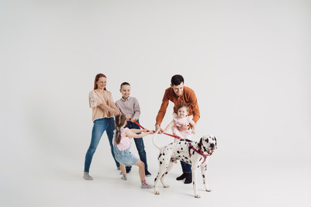 Young Family with kids playing with a dalmatian dog on white backgroundの写真素材