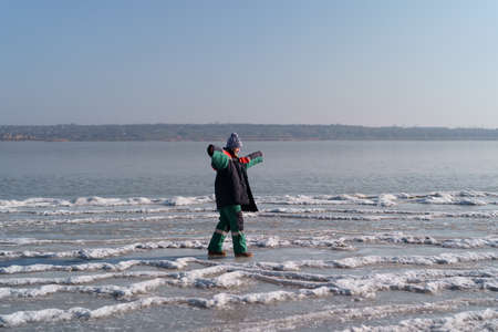 A woman in a colorful thermal costume enjoying winter while standing on a frozen lake with blue sky in the background. Freedomの写真素材