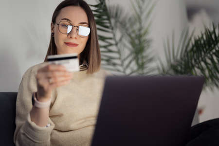 Online shopping using card and laptop. Caucasian woman using technology to shop while sitting on a...