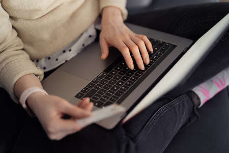 Online shopping using card and laptop. Woman handsusing technology to shop while sitting on a sofa indoorsの写真素材