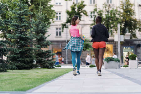 Back view of friends in sportswear running in the city dicussing. Multiethnic women having a fitness workout.の写真素材