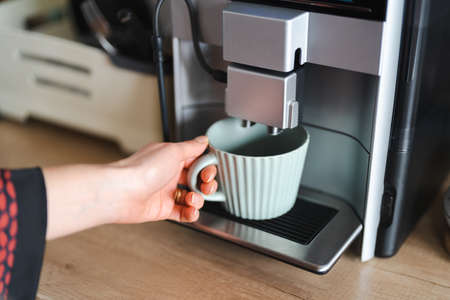 Close-up image of woman hand using coffee machine when making big mug of coffee at homeの写真素材