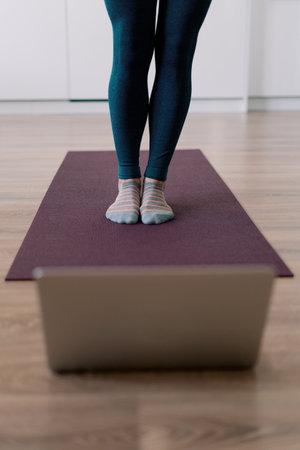 Womans legs practicing yoga at home using online training instructions
