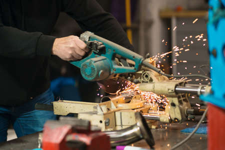 Technician worker cutting metal with many sharp sparks. Using equipments to cat iron