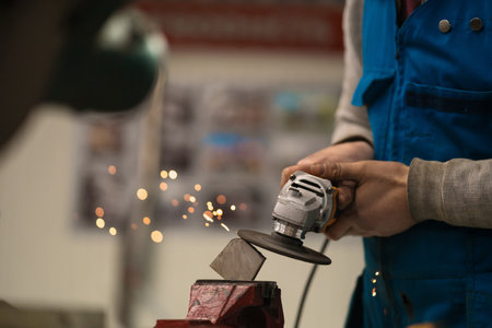 Technician worker cutting metal with many sharp sparks. Using equipments to cat iron