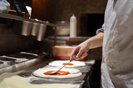 Pizza making process. Male chef hands making authentic pizza in the pizzeria kitchen.の写真素材
