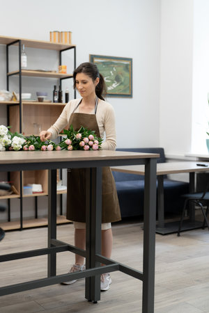 Florist woman working with flowers making a composition in her workshopの写真素材
