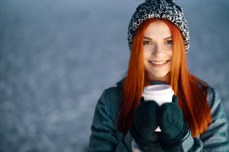 Girl drinking hot coffee while walking in the evening. Feeling happy in big city. Spending winter vacationsの写真素材