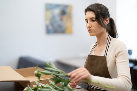 Woman Florist working in her workshop with flowers making a composition box on orderの写真素材