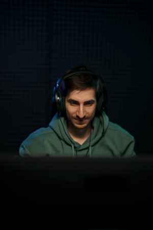 Cheerful male cybersport gamer sitting with hands behind head after successful game