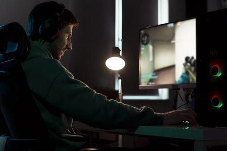 Focused cybersport gamer playing video game on computer