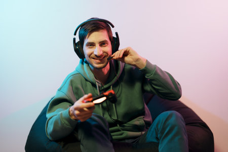 Happy male gamer in headset with gamepad playing video game