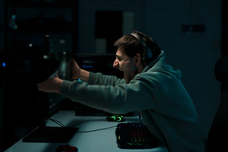 Happy male cybersport gamer embracing computer while rejoicing over victory