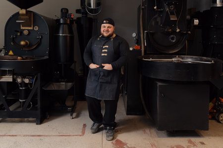 Male worker standing near professional roasting machineの写真素材
