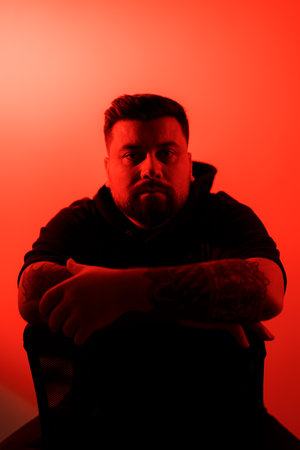 Serious bearded man in shadow against neon illuminationの写真素材