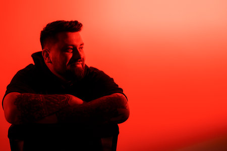 Serious bearded man in shadow against neon illuminationの写真素材