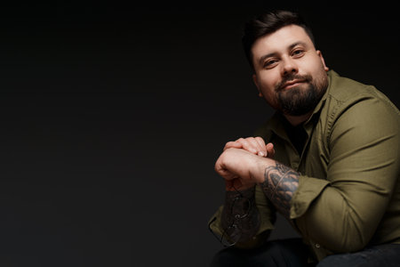 Cheerful bearded man with eyeglasses smiling at camera in darkの写真素材