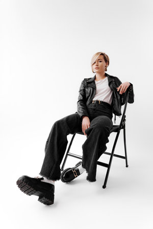 Stylish woman in black jacket sitting on chairの写真素材